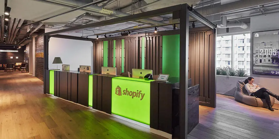 The Shopify reception desk at an office, lit in the company's green.