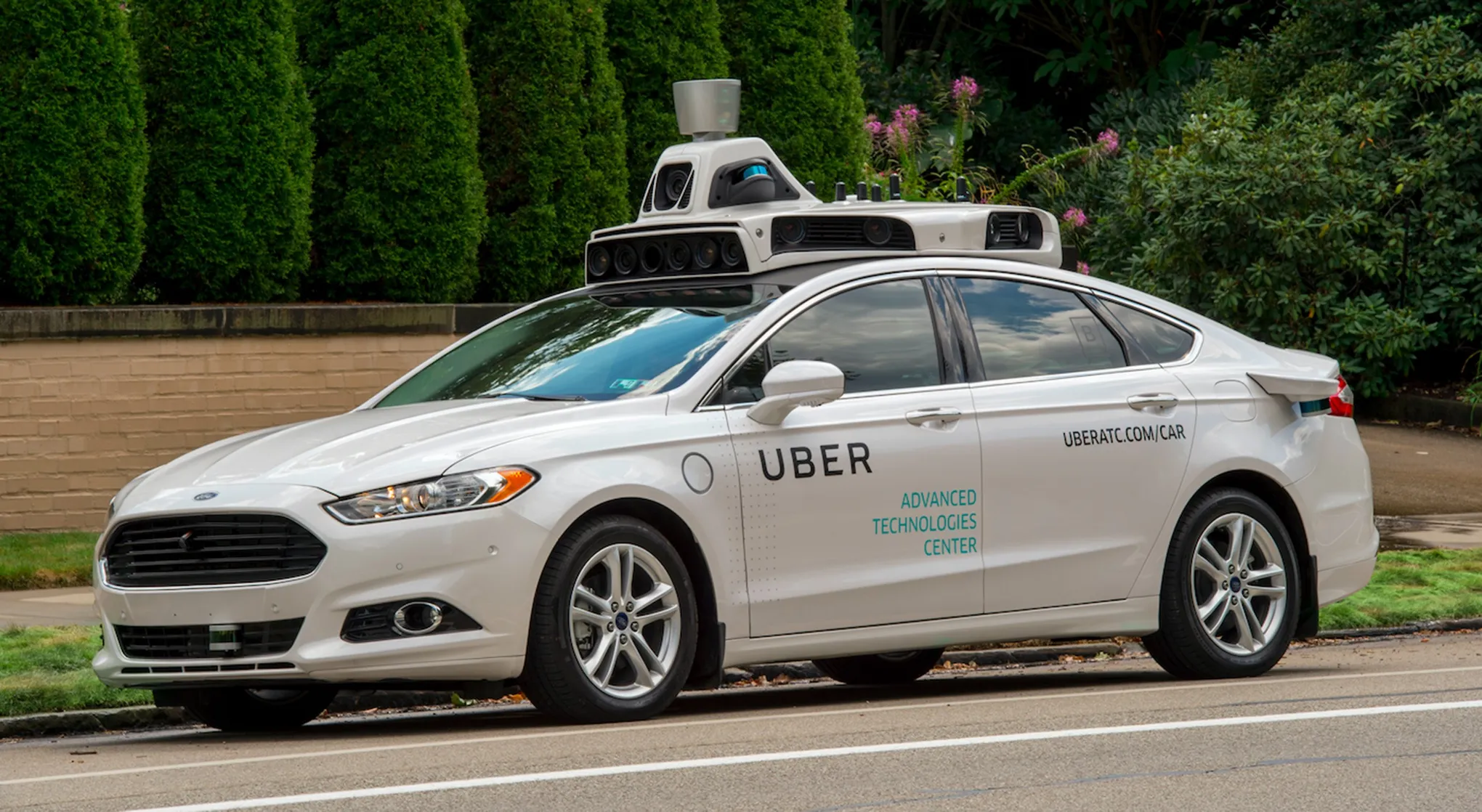 An Uber self-driving test vehicle, fitted with sensor and lidar equipment, parked on a residential street.