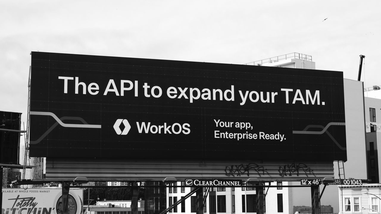 A black-and-white photo of a roadside billboard reading 